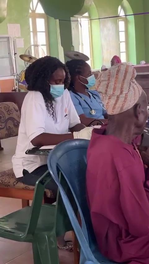 Video of volunteer health workers providing care to community elders during an outreach mission — examination, paperwork, and patient interaction.